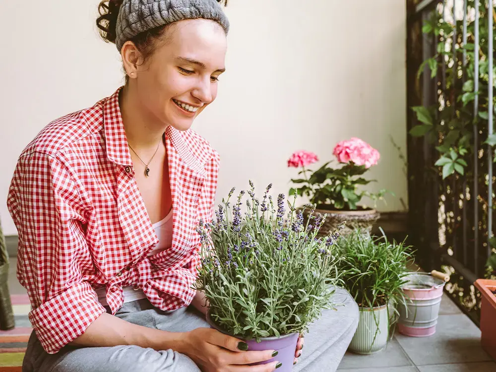 Jonge vrouw met een lavendel plant in haar handen.